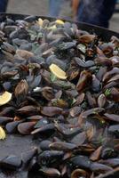 Close up of cooked mussels at a street food festival, ready to eat seafood photographed with soft focus
