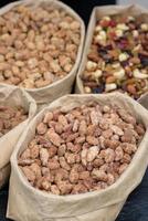 Almonds and pistachios with spices lie in paper bags on the counter.
