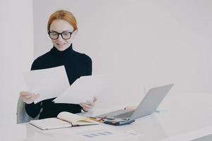 Happy european business lady is doing paperwork and smiling. Concept of business success. photo