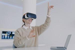 Young european woman in VR goggles in office. Student is working on futuristic design in cyberspace. photo