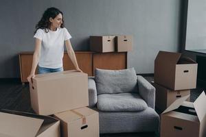 Proud single european lady in casual outfit moves. Cardboard boxes on floor. Real estate purchase. photo