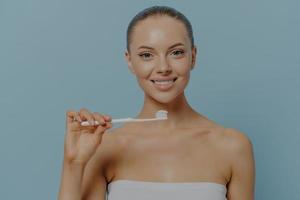 dental. joven hermosa mujer sana sosteniendo cepillo de dientes, cepillando los dientes con pasta dental con fluoruro foto