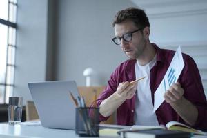 Young european man office worker in glasses showing statistics report during online meeting