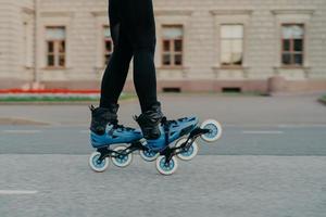 Cropped shot of faceless woman wears rollerblades for riding on road enjoys hobby in fresh air has active lifestyle tries new rollers after purchasing. People hobby and outdoor free time activities photo