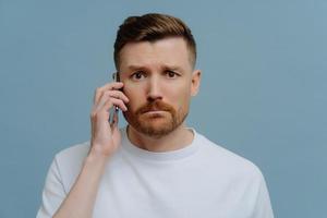 Worried man receiving bad news while talking with somebody on mobile phone photo