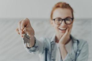 Happy female owner of new flat shows keys being glad renter or buyer