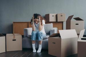 Tired european woman sitting among packed boxes. Hopeless young lady getting in trouble photo