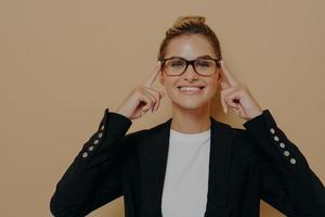 Positive blonde female student putting on eyeglasses and holding them with hands photo