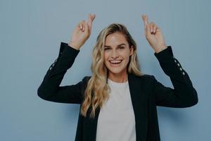 Excited blonde girl wishing with crossed fingers photo