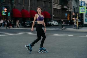 tiro completo de mujer joven delgada activa vestida con ropa deportiva paseos en rodillos para fortalecer los músculos de los brazos y las piernas mejora la agilidad del equilibrio y la coordinación tiene buen humor quema calorías foto