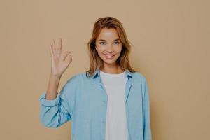 Close up portrait of cheerful pretty brunette female dressed in blue shirt photo