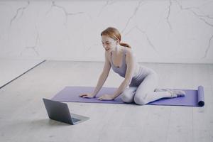 Young woman practicing yoga internet fitness lesson on self isolation. Home online classes.