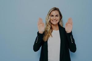 Woman refusing in polite manner smiling friendly with positive look as waving hands in stop gesture photo