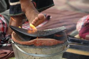 Iron plow plate is on clay fire pot and blur foot touch fire above plow plate. Preparation equipment set for Thai massage in Northern style. photo