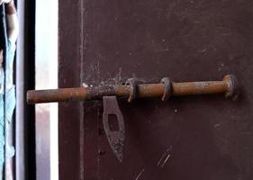 A dark brown painted door lock made from iron in ancient style, Thailand. Rusty on surface of door lock. photo