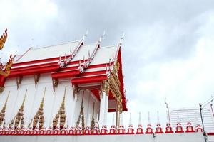 Beside red and white colr church in Thai ancient style of WatKhunyingsomjean and cloudy sky background, Thailnad