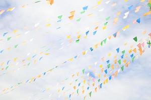 Blue,green, yellow, white triangle flags are on lines and sky background. photo