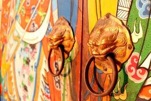 Brass door knobs are on bright colorful door and shape tiger head, the door knobs are design chinese style in shrine, Thailand.