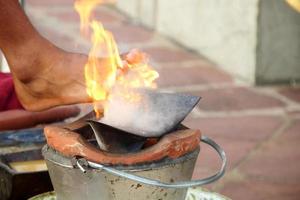 una olla de barro y una placa de arado de hierro están sobre ella, el pie toca el fuego sobre la placa de arado. equipo de preparación para masaje tailandés al estilo norteño. foto