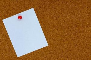 Blank white paper note pinned to a cork board. photo