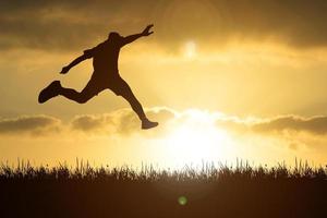 The silhouette of a man is jumping forward. The concept of clawing through hurdles photo