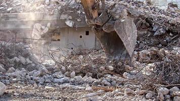 el hierro y el hormigón de un edificio destruido con la ayuda de una excavadora de demolición se preparan para su reciclaje.