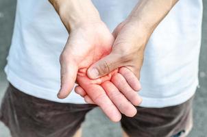 hombre sosteniendo su mano - concepto de dolor que sufre foto