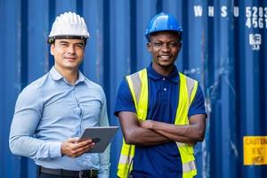 Confident port manager and engineer while stand crossed arms and smiling at freight containers photo