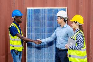 Foreman shaking hand to a Businessman and his woman colleague team in front of solar panels . Solar panels in the field, business deal between client and foreman. photo