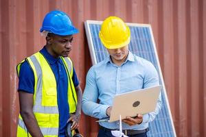 equipo de dos ingenieros de energía masculinos discutiendo un nuevo proyecto a punto de invertir en la instalación de células solares fuera del edificio o fábrica industrial