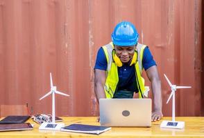Ecology engineer typing on laptop and working on project. On desk are windmill models. Sustainable development concept photo