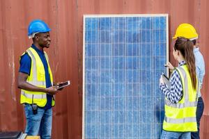 dos ingenieros de energía masculinos con su colega mujer discutiendo un nuevo proyecto a punto de invertir en la instalación de células solares fuera del edificio o fábrica industrial foto