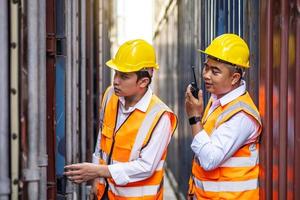 profesional de dos ingenieros o supervisores que revisan y controlan la caja de contenedores de carga de la carga en el puerto. concepto de transporte y logística foto