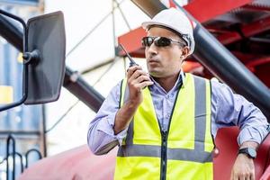 joven ingeniero o gerente que usa la comunicación por radio para controlar la carga de contenedores en conceptos de logística y transporte industrial. foto