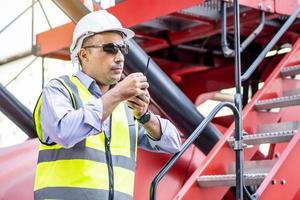 joven ingeniero o gerente que usa la comunicación por radio para controlar la carga de contenedores en conceptos de logística y transporte industrial. foto