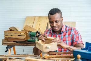 joven carpintero afroamericano mira con orgullo una casa de madera modelo. cuando tiene éxito foto