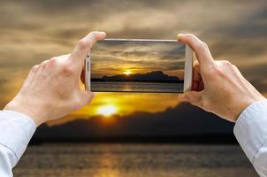 vista recortada de las manos del hombre haciendo fotos en la cámara del teléfono móvil es alta montaña con picos iluminados en tailandia