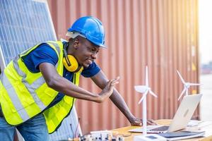 A male engineer using laptop, making video call to client or business partner by the negotiations were successful., On desk are windmill models. Sustainable development concept photo
