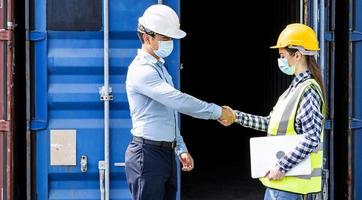 Businessman and engineer woman shake hands as hello in the container cargo harbor to loading containers. Shaking hands after the inspection or investigation are complete. Industrial and business photo