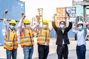 Group of employees and management team wearing logistic uniforms for exporting products abroad, stand to celebrating or raise their hands together to manage at the container yard photo