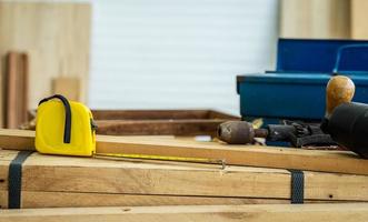Background image of carpenters workstation, carpenters work table with different tools, unfolded measuring tape on a wooden board, wood cutting with wood shavings