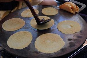 Crispy crepe base of Thai ancient crispy crepe are grilling on hot plate. Thai crispy crepe are in round and small shape, Thailand. photo