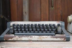 Old typewriter and brown wood background.The typewriter has brown rush on base. photo