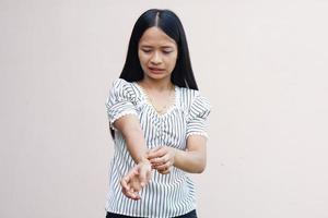 Woman scratching arm from itching on light gray background. Cause of itchy skin include insect bitesConcept of health care skin. photo