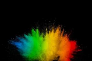 Abstract multicolored powder explosion on black background. Color dust particle splattered on background. photo