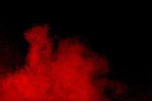 polvo rojo abstracto salpicado sobre fondo negro. explosión de polvo rojo. movimiento congelado de salpicaduras de partículas rojas. foto
