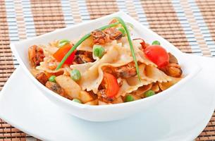 pasta farfalle con mariscos, tomates cherry y guisantes verdes foto