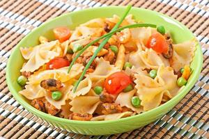 Farfalle pasta with seafood, cherry tomatoes and green peas photo