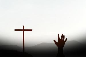 human hand silhouette asking for help from the cross representing Jesus photo