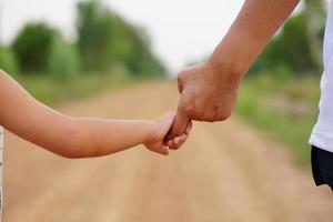 Mother's hand holding a little girl's hand on bokeh background. Love and family concept. photo